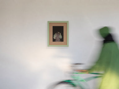 »Liminal« von Janine Kühn — Fotografie einer verwischten Figur in hellem Kleid vor dunklem Grund, gerahmt in Mintgrün mit Glaspassepartout, Frameworks Berlin