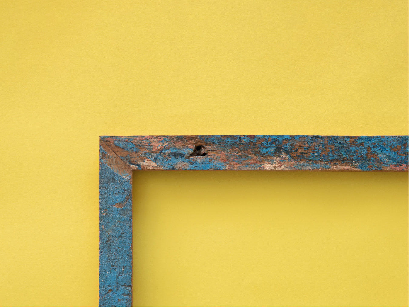 Frameworks_blauerBilderrahmenausrecaceltemHolzmitabblätternderFarbevorgelberWand
