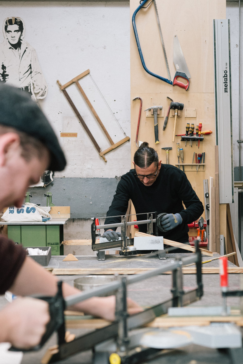 Handwerker sägt präzise eine Holzleiste für einen Bilderrahmen in der Frameworks Berlin Werkstatt
