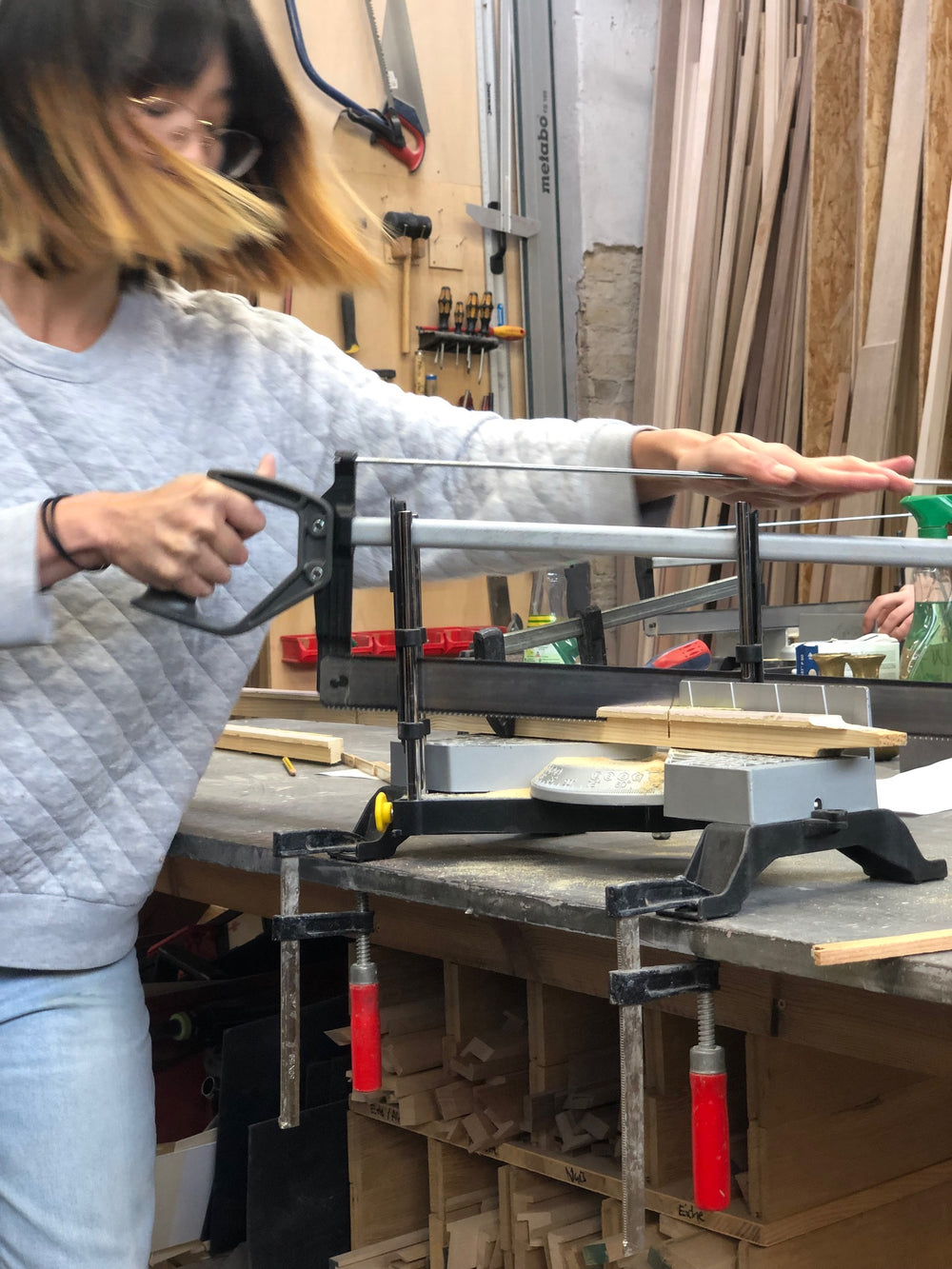 Handwerkerin sägt eine Bilderrahmenleiste aus Holz präzise im Frameworks Berlin Werkstatt.